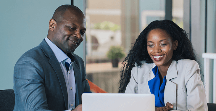 A non-Caucasian couple is chatting while looking at their laptop